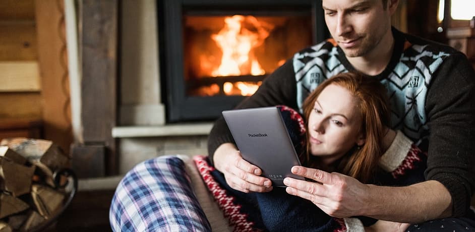 Ein Foto von zwei Personen vorm Kaminfeuer mit einem E-Reader in der Hand